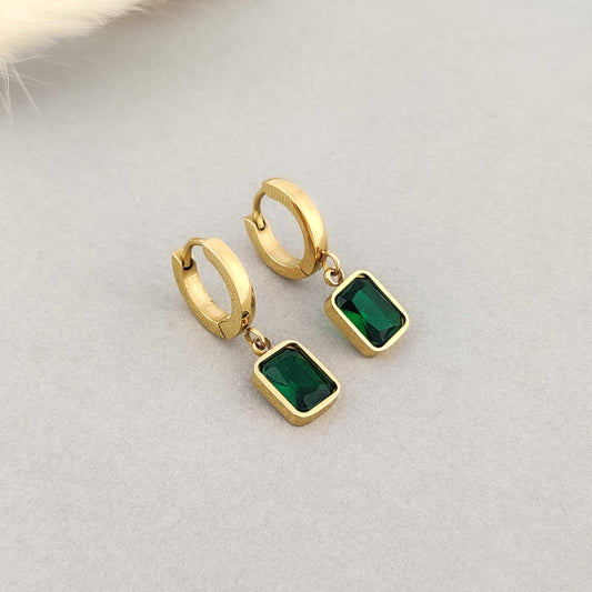 "Women’s gold huggie earrings with emerald green crystal pendant."