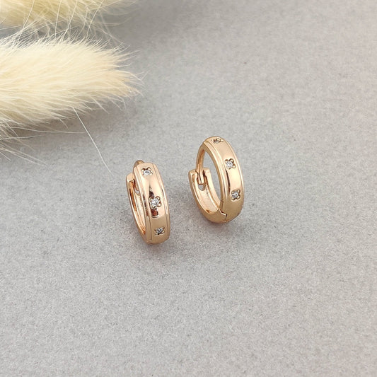 "Women’s rose gold huggie earrings with CZ floral detailing."