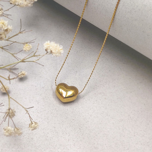 "Close-up of delicate gold chain necklace featuring a polished heart-shaped pendant"