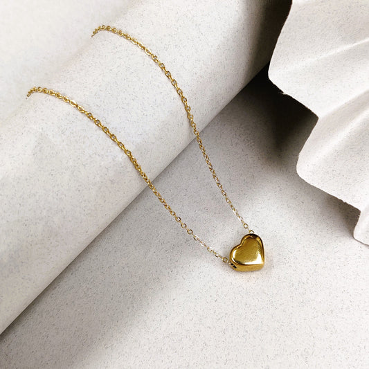 Gold heart pendant necklace on a delicate chain, showcasing elegant jewelry design, perfect for romantic or special occasions, displayed on .