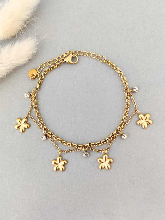 “Layered gold charm bracelet with flower pendants and crystal stones for women.”