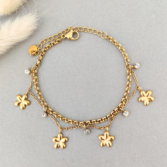 “Layered gold charm bracelet with flower pendants and crystal stones for women.”