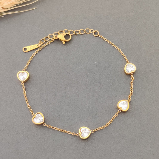 “Delicate gold bracelet featuring sparkling CZ heart charms.”