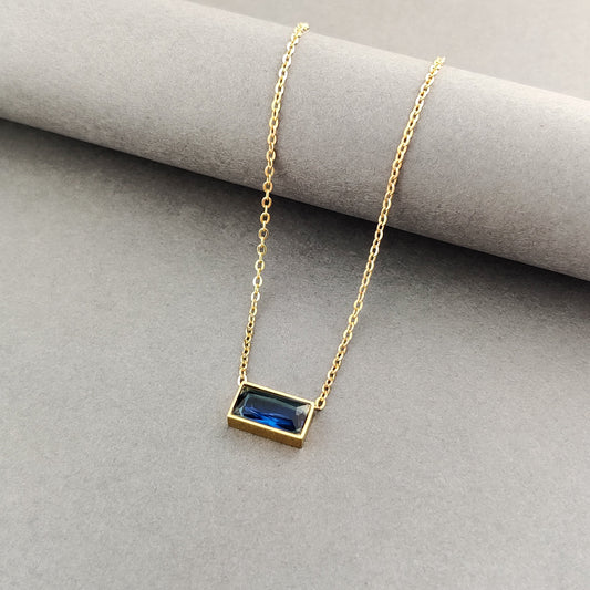 "Minimalist gold necklace with an east-west set blue rectangular crystal, ideal for layering."