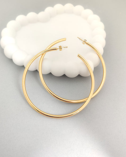“Women’s gold hoop earrings – sleek lightweight hoops on modern white jewellery tray.”
